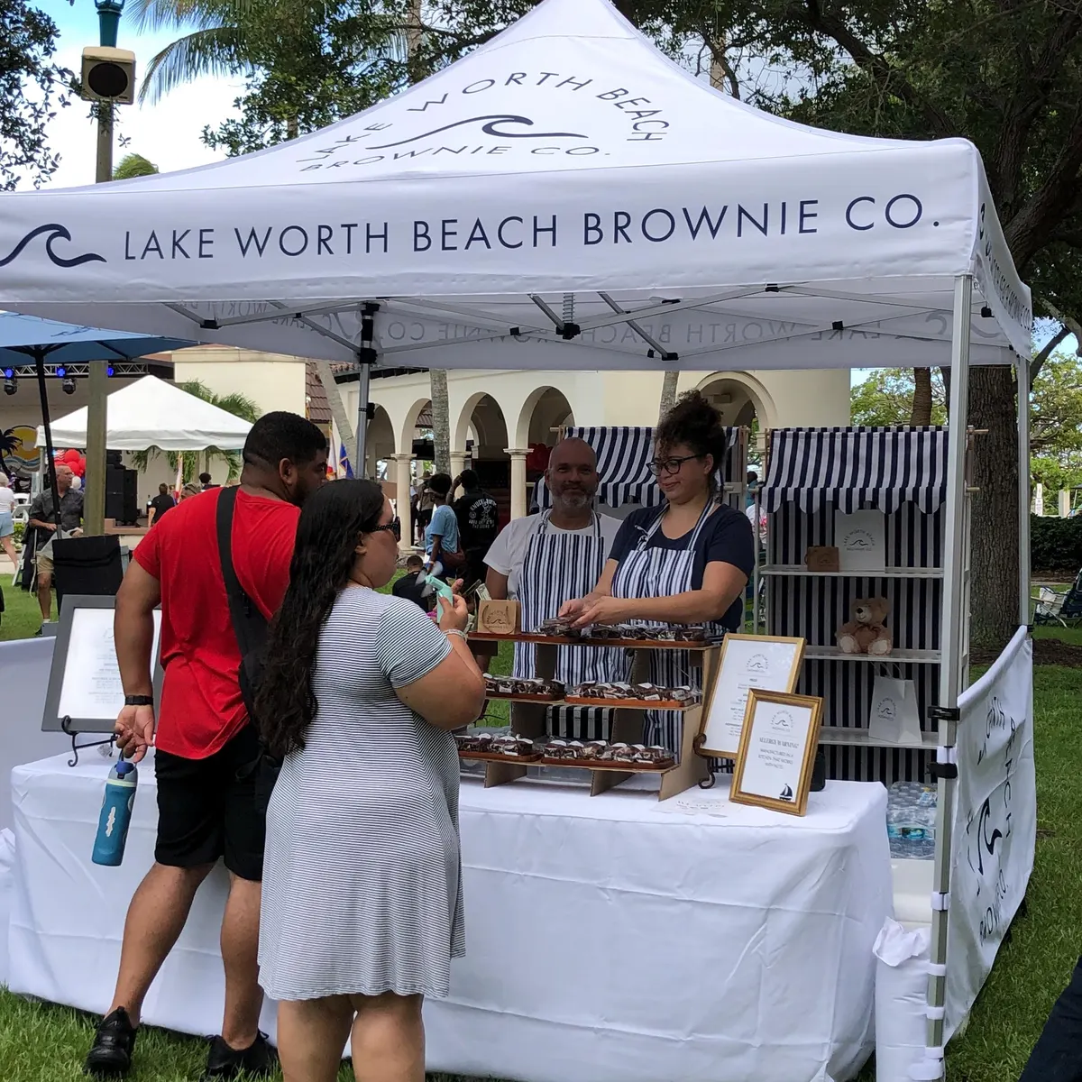 Lake Worth Beach Brownie Co. custom printed white 10x10 canopy tent with striped backwall and table cover at an outdoor market