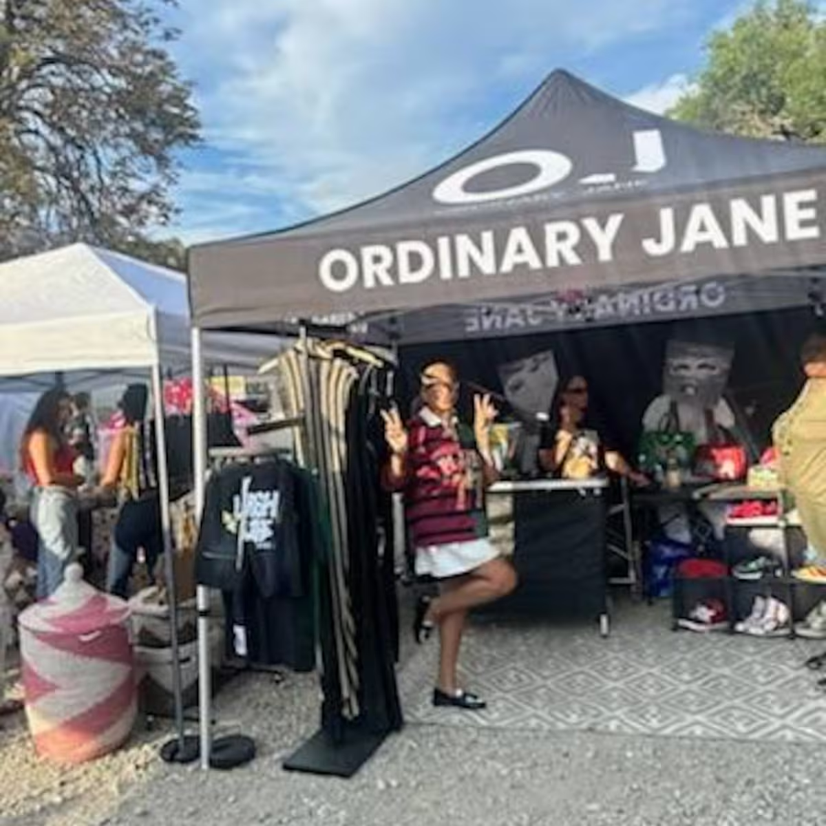 Branded black pop-up canopy tent used as a boutique booth at an outdoor market